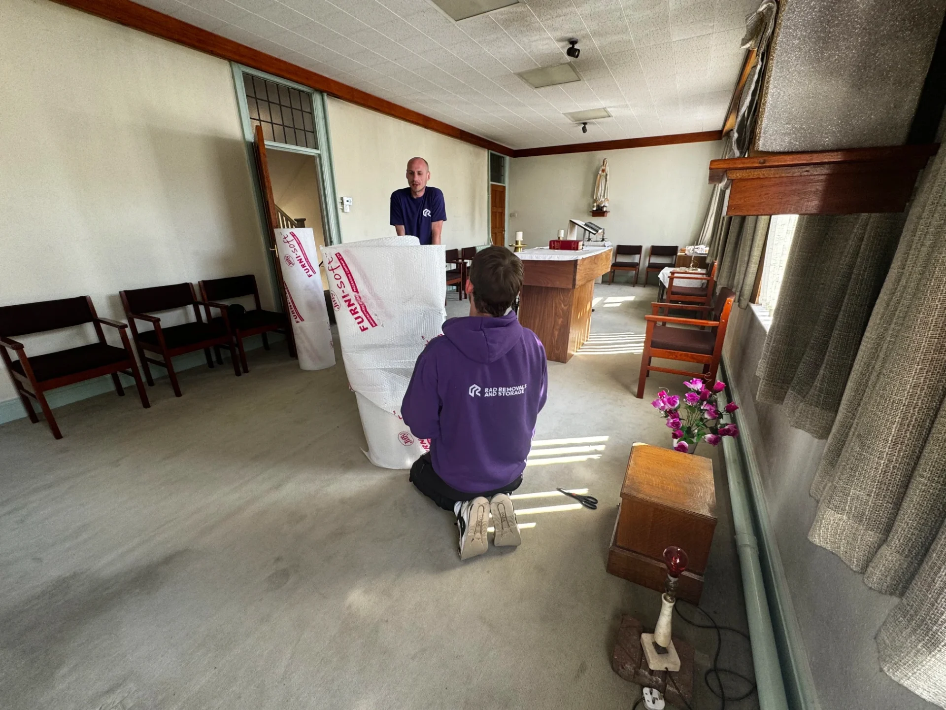 Rad Removals team carefully wrapping furniture in Furniguard inside a historic London chapel